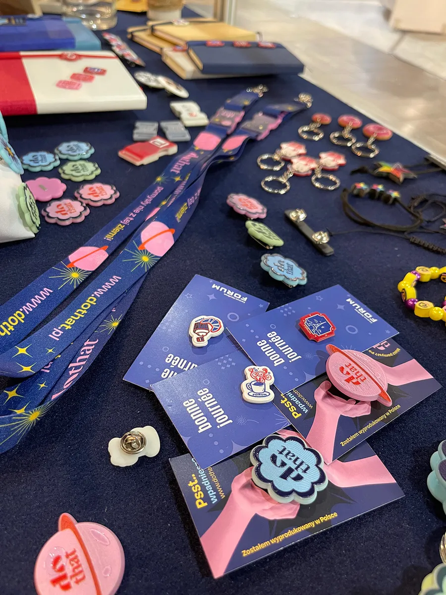 Lanyards with personalised buckles, pins and dothat keychains laid out on a navy table