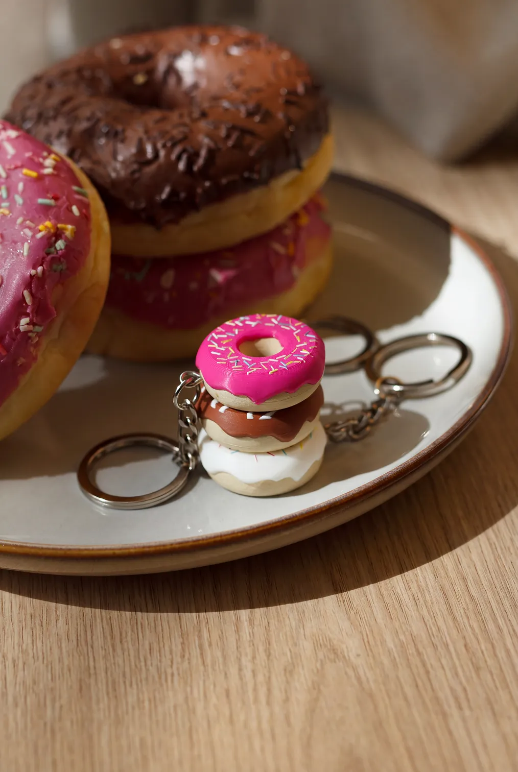 Brelok w kształcie stosu donutów na talerzu obok prawdziwych donutów