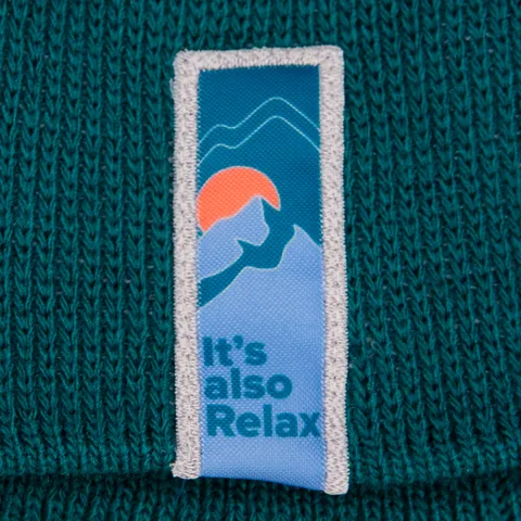 Woven logo label sewn into green knitted fabric, edged with reflective thread